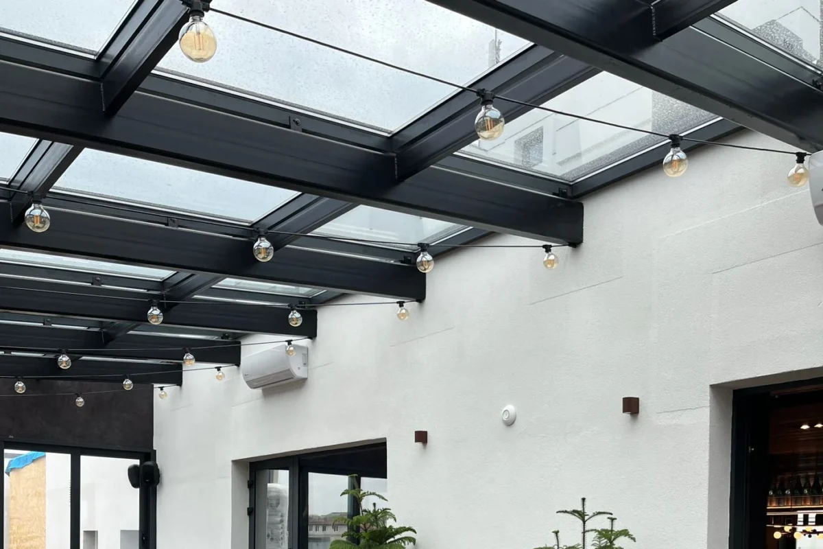 Terraço coberto com cobertura de vidro sobre estrutura metálica escura