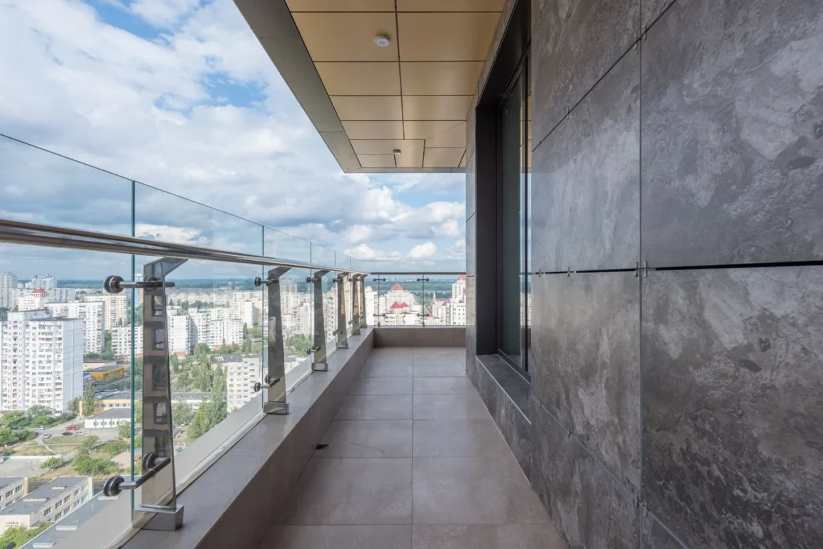 Terraço de apartamento com barreira de vidro e corrimão metálico