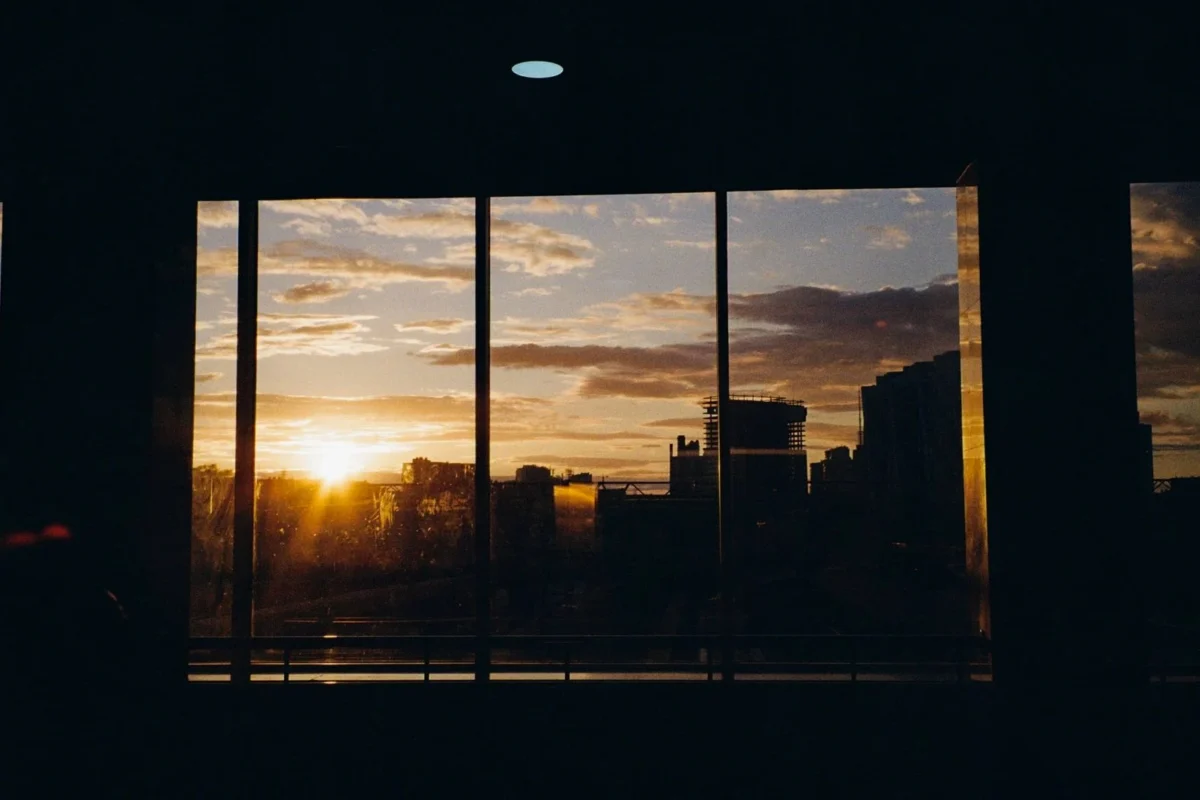 Vista urbana ao entardecer através de janelas altas de vidro